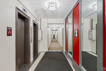 A long hallway with red doors and a red stop sign on the wall.